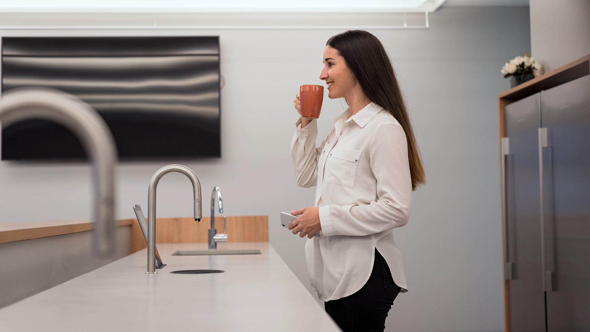 Employee enjoying a coffee served from the TopBrewer coffee machine installed in their work place kitchen