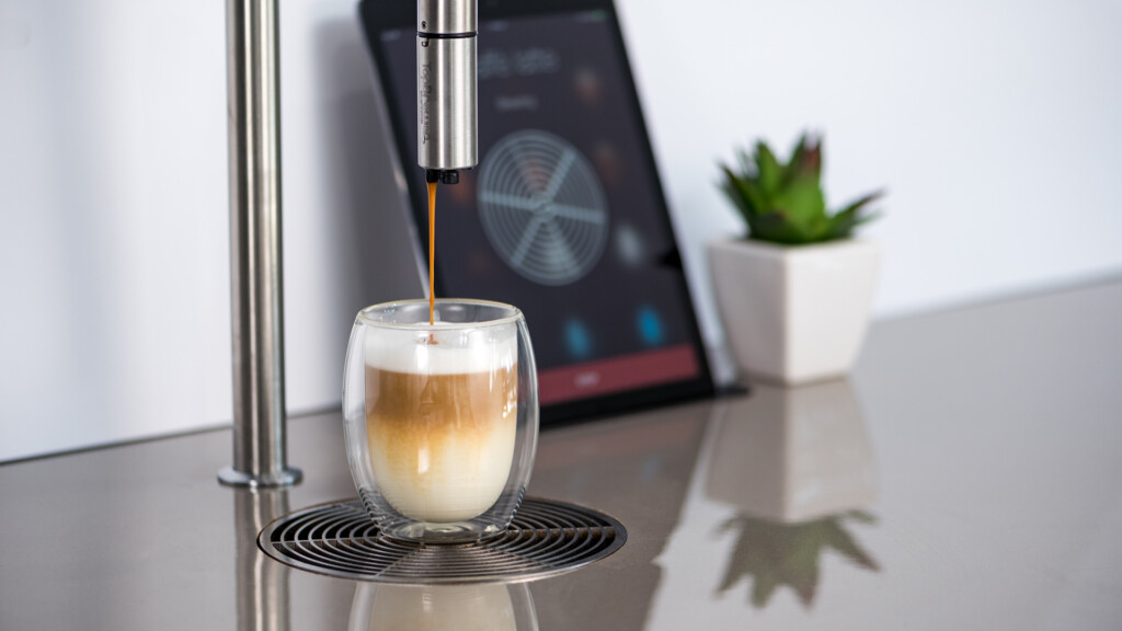 TopBrewer Coffee machine serving coffee into a glass mug with the self serving iPad in the background