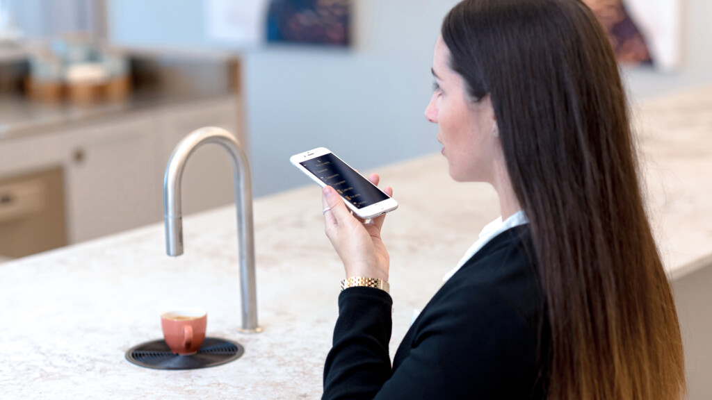 Employee using the voice activation function on the TopBrewer app to order her coffee from the TopBrewer installed in the office kitchen.