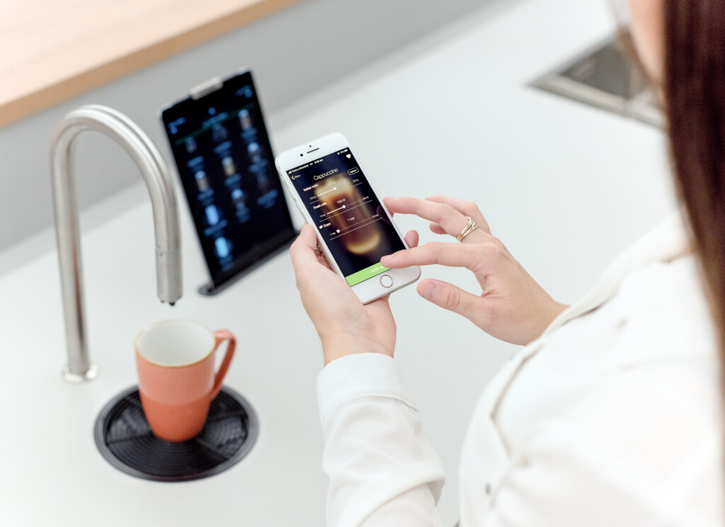 Employee in front of a TopBrewer coffee machine installed in an office selecting their coffee using the TopBrewer app